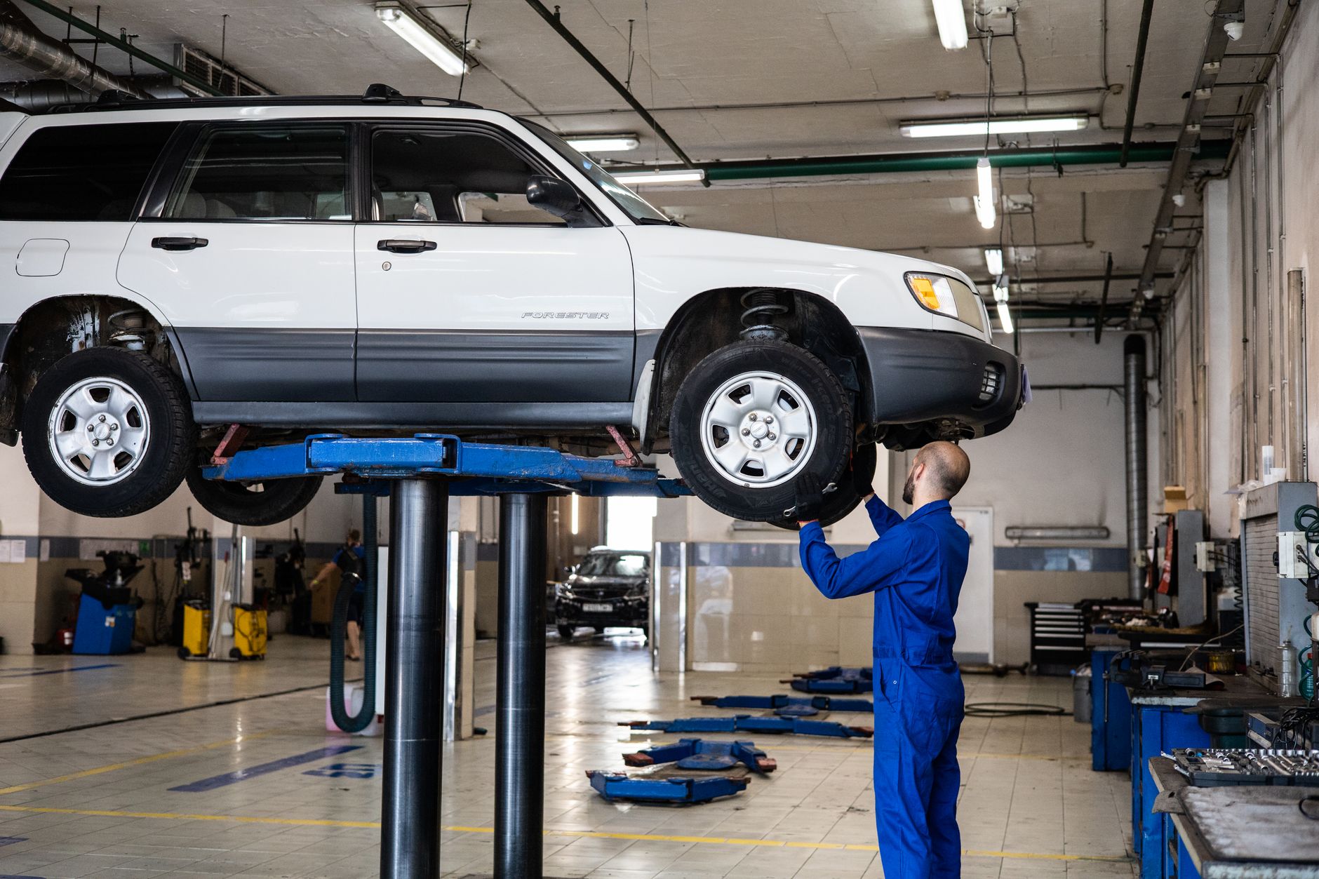 Mechanic inspecting a car lifted in an auto repair shop